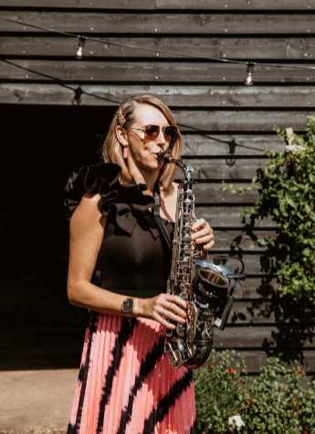 Kay with Sax infront of a wooden Barn